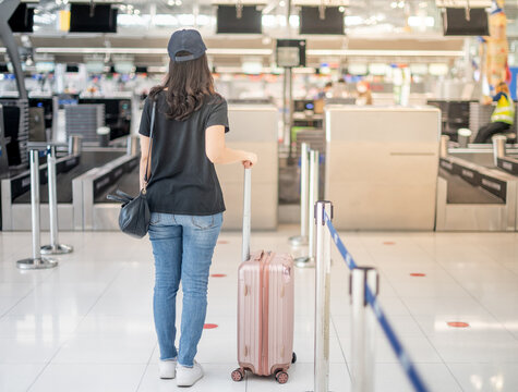 The back view of asian woman traveler carrying luggage prepare to check-in at the counter check in in the airport