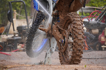 レース後、泥だらけのオフロードバイクを洗車する様子/The motocross bike covered in mud is washing after race.