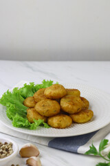 Perkedel Kentang or Potato cutlet, one of Indonesian food made from mashed potato, celery, spice, and fried. White marble background, copy space for text