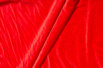 Colored red textile satin fabric folded in folds and waves with highlights and texture