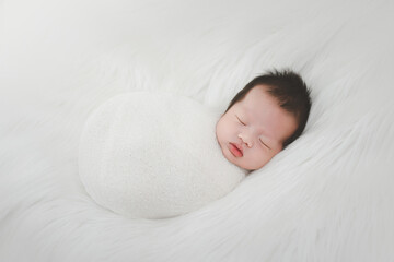 Newborn infant boy asian image Sleeping a few days old A newborn boy sleeps wrapped in prom silk knit on a wool rug, ideal for a newborn baby photoshoot. © Kritsada