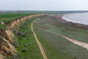 The coast of the Kuyalnitsky estuary in the spring. Sandy cliff, beach and pond. Aerial view.