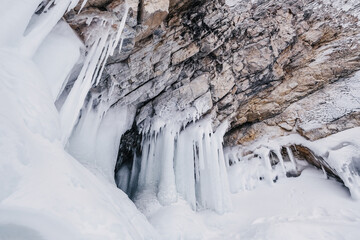 Ice caves grottoes with icicles in the rocks on the winter lake Baikal