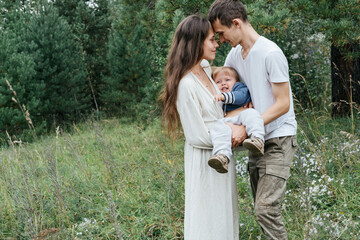 Happy funny Young family father, mom and baby boy walking and playing outdoor together near fur forest in summer day