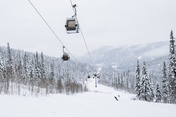 Fototapeta na wymiar Gondola lift in the ski resort on snow covered slop, winter trees, mountains landscape