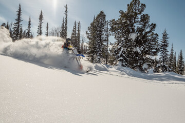  Rider on snowbike in beautiful mountain landscape, puffs of snow behind motorcycle