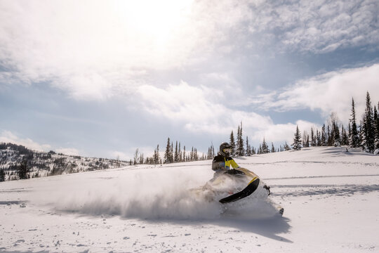 Snowmobile female rider riding on beautiful mountain slope
