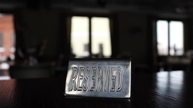 A plate reserved on a dark table in a cafe opposite the windows. High quality FullHD footage