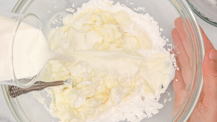 Cream cheese, powdered sugar and milk cream mixing in a glass bowl, flat lay. Whipped cream cheese desert recipe