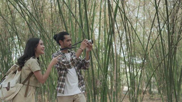 Male and female tourists are taking nature tours and taking pictures of the scenery. Female tourists are touring the woods with their boyfriend on their weekly vacation. Concept of nature tourism.