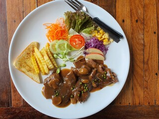 Pork Steak with Salad and French Fries on White Plate  On a wooden table, Rayong, Thailand, May 20, 2021
