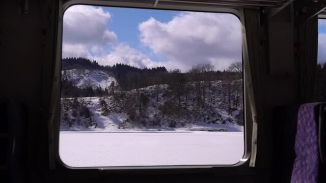 Beautiful snowy landscape scenery passing by in front of window from train interior