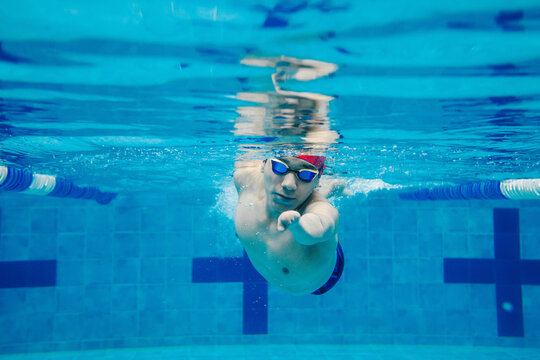 portrait of paralympic Swimmer young mexican man Underwater Training In Pool with hand hypoplasia in disability concept