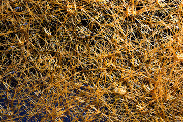 Abstract background of yellow plastic threads on a dark background