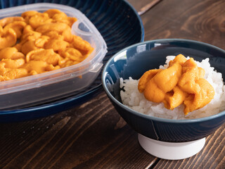 新鮮な雲丹が乗ったご飯とプラスチック容器に入ったウニ。