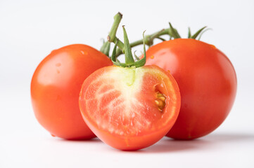 Fresh tomatoes on a green stem on white