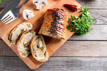 Sliced roast pork roulade - Porchetta, served on a wooden table, close-up, flatlay, copy space