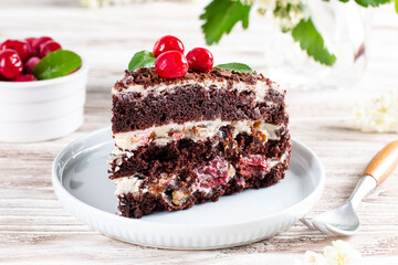 Chocolate layered sponge cake with cherries on a plate on a table