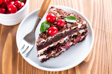 Chocolate sponge cake with cherries on a plate on a table