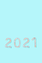 Number 2021 from white and soft pink shells on turquoise color paper. Summer design concept with seashells.