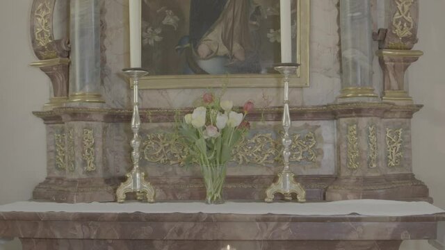 Baroque altar of the Virgin Mary with candles in a church, camera pan from bottom to top
