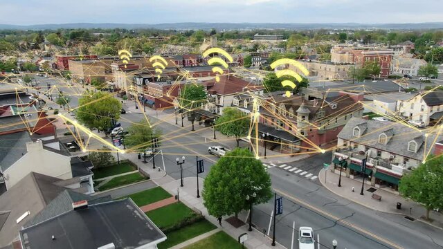 Internet web and data speed signals overlays small town in USA. Rural public broadband expansion and community access.