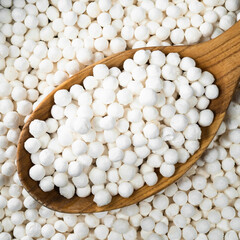 raw tapioca pearls in wooden spoon closeup