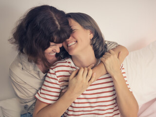 Beautiful women LGBT lesbian happy couple sitting on bed and hugging at home.