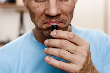Young ill man trying to sense smell of tube essential oil