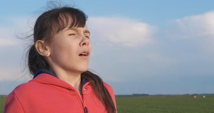 Cough and allergy. A pretty child cough and sneeze in the green field in the day light.