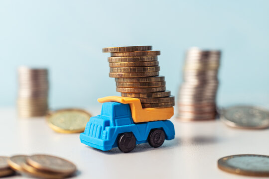 small truck with a stack of gold coins on it. there are stacks of other coins lying around.