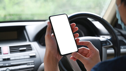 Cropped shot of businessman wearing protective mask sitting in car and using mobile phone.