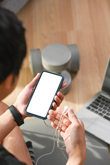 Close up view of sportsman using smart phone and exercising at home.