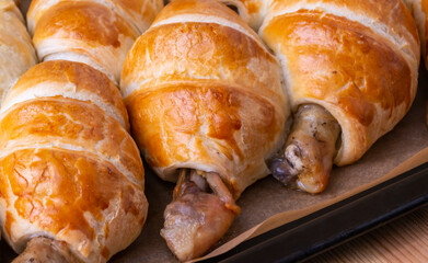 Appetizing chicken leg in puff pastry on a baking sheet