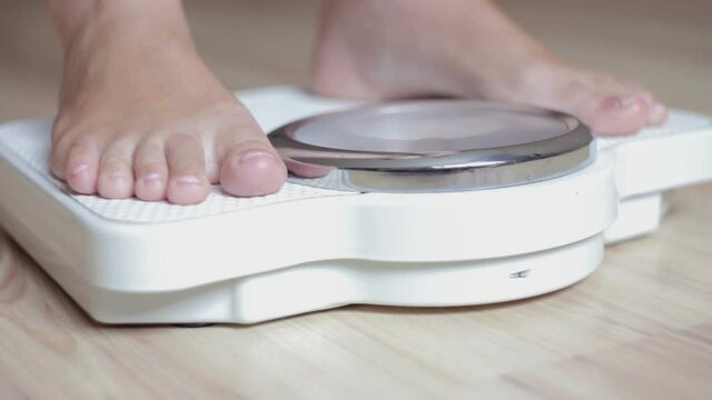 Young woman checking her weight. Close-up of female legs on the scales.