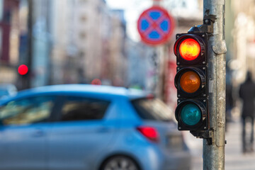closeup of small traffic semaphore with red light against the backdrop of the city traffic