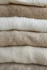 Fototapeta na wymiar cozy milky beige and white natural wool sweaters, folded on a white background close-up. clothes made of merino wool, alpaca, natural eco-fabrics. the concept of conscious consumption. mockup