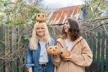 Couple of laughing teenagers with halloween pumpkins having fun