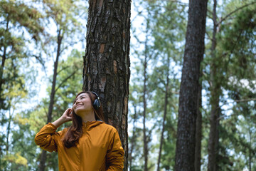 Portrait image of a beautiful young asian woman enjoy listening to music with headphone in the park