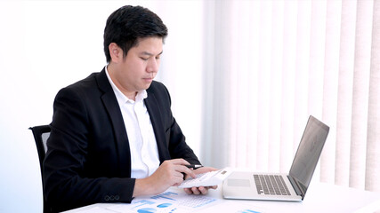 Business concept a male accountant using a calculator counting company’s profits and losses, preparing financial reports for business.