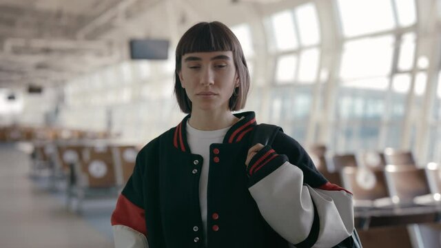 Confident woman in stylish bomber jacket waiting for flight