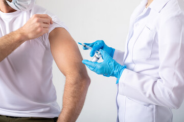 Doctor holding a syringe before injecting coronavirus vaccine into a male patient.