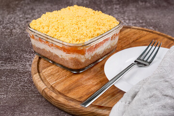 Traditional russian salad Mimosa with vegetables and fish. Layered salad with potatoes, tuna, carrot, onion, eggs and mayonnaise.