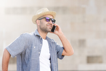 Dark-skinned hispanic hipster man wearing a straw hat and talking on the phone.