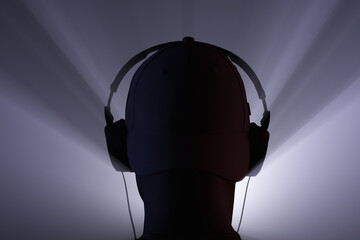 Silhouette of a head with headphones in the beams of the spotlight