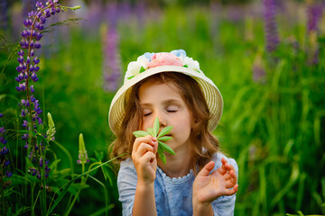 A girl in a lilac flower meadow hugs and sniffs a large lupin leaf