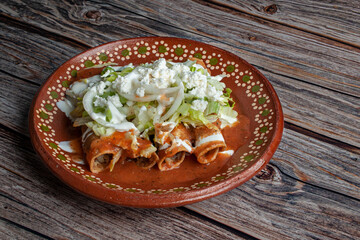  Beef and potato tacos dorados with lettuce white onions cream and tomato salsa on top. Fried tacos as part of Mexican food 