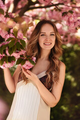 Naklejka premium Beautiful young woman in the spring garden. Girl near sakura 