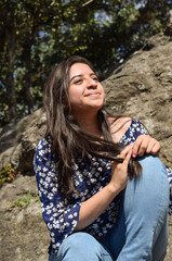 Mujer Joven Guatemalteca sentada sobre una roca, disfrutando del sol y la naturaleza al aire libre.
