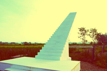 The steps of a white staircase lead to the sky..